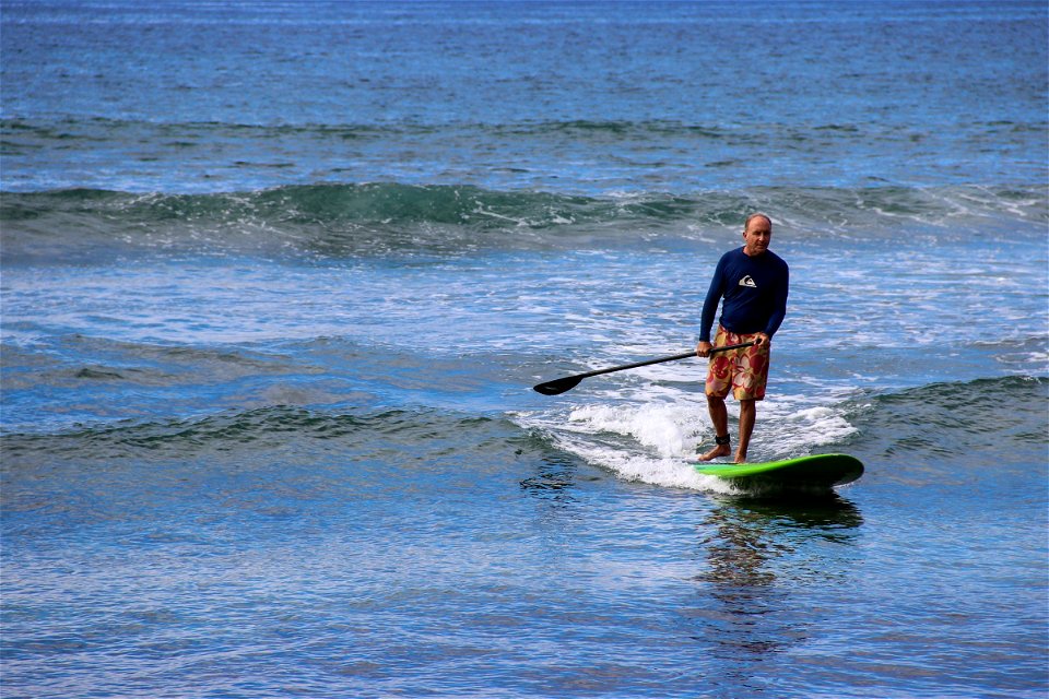 Man Riding Paddle Board in Ocean photo