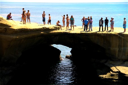 People Standing on Rock Ledge Over Ocean photo