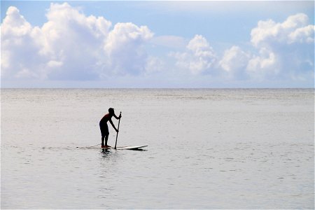 Man Paddling on Surfboard in Ocean photo