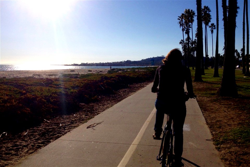 Woman Riding Bicycle on Path by Beach photo