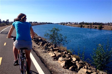 Woman Riding Bike on Path Along River photo