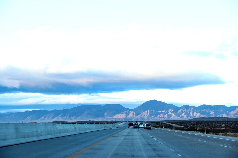 Cars on Highway in Desert Towards Mountains