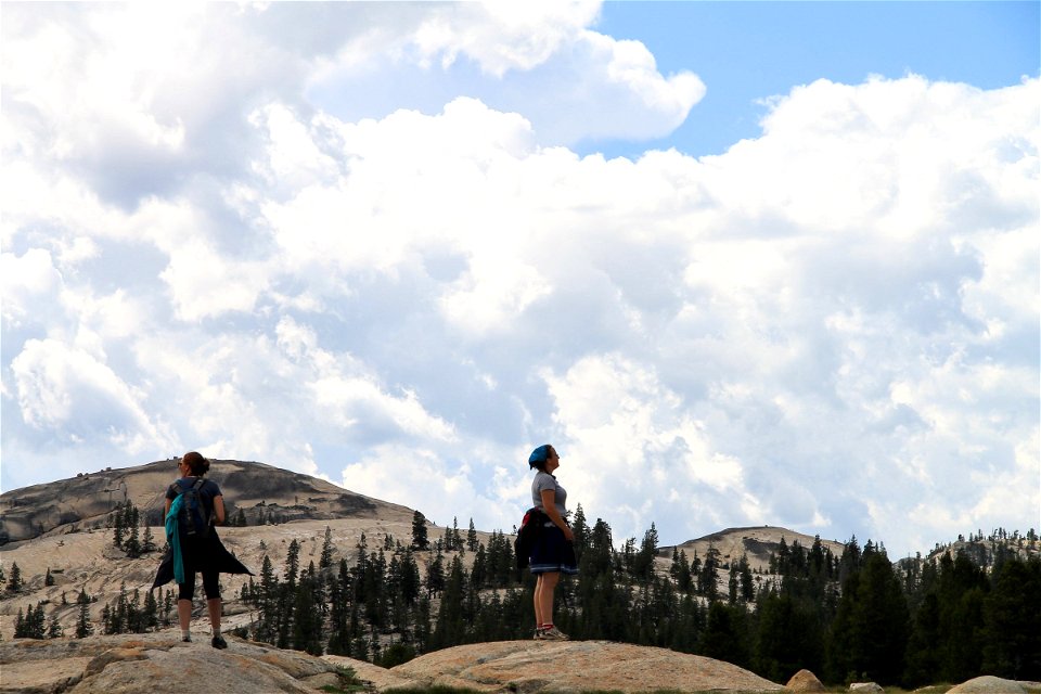2 Women Standing on Rocks Under Sky of Clouds