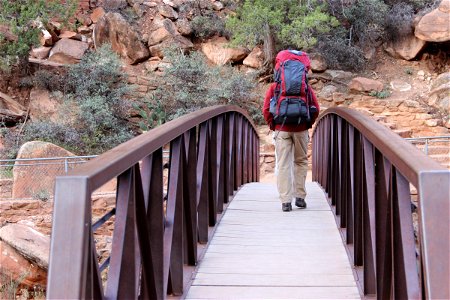 Man with Hiking Backpack Walking Across Bridge photo