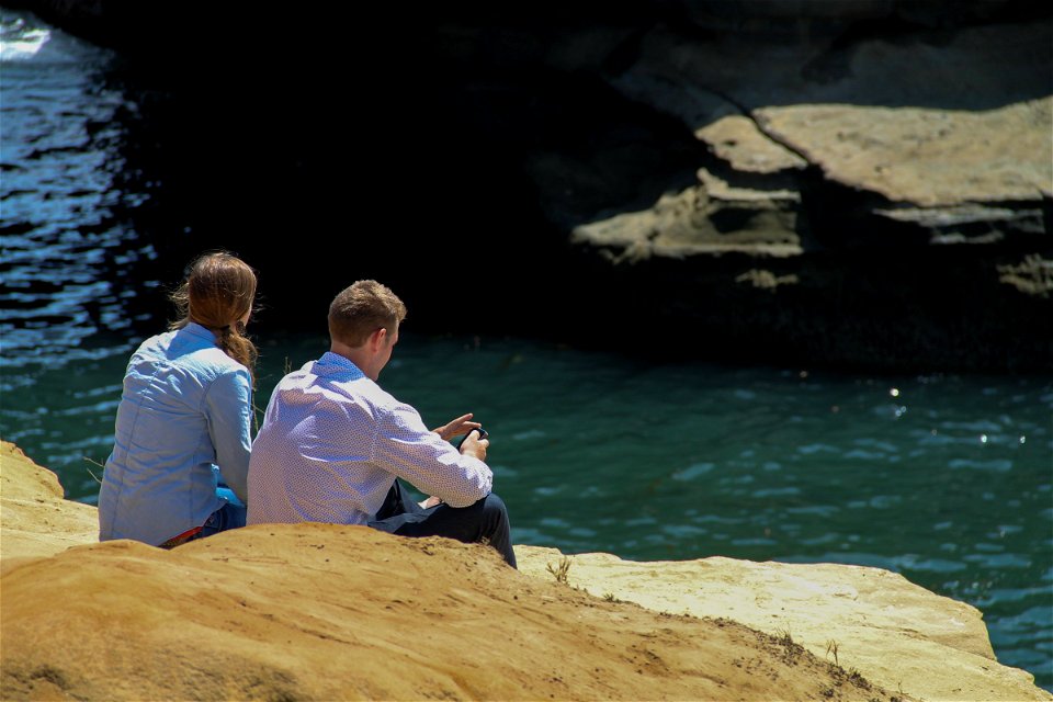 Young Couple Sitting on Rocks by Water photo