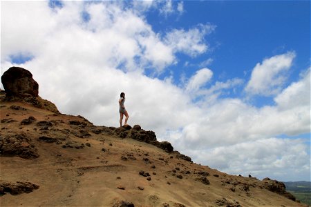 Woman on Rocky Hill Against Clouds photo