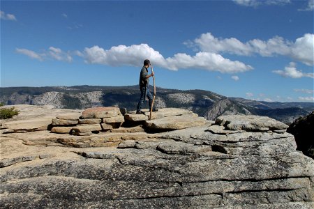 Man with Staff on Rocks Looking at Mountains photo