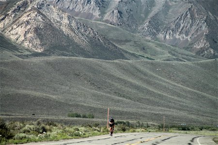 Bicyclist on Road with Mountain Behind photo