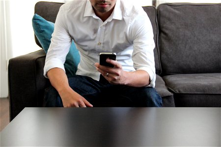 Man Sitting on Couch Using Phone photo