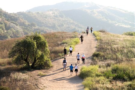 People Walking on Dry Dirt Trail Over Hill photo