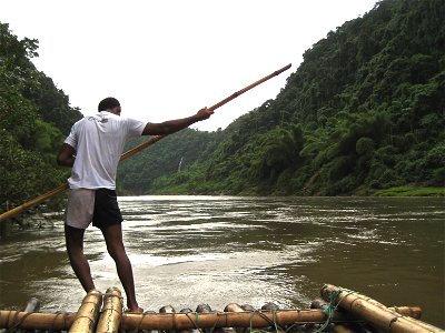 Man with Pole on Bamboo Raft in River photo