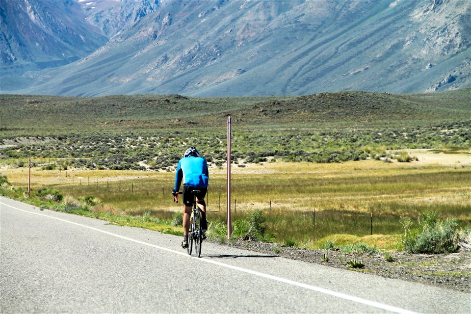 Bicyclist on Road by Fields & Mountain photo