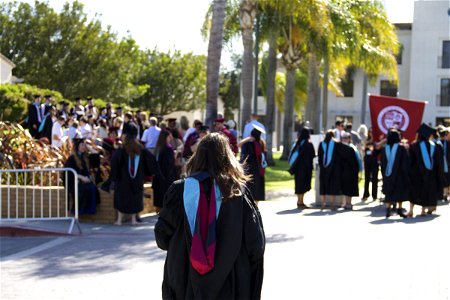 Girl in Graduation Robe Walking to Crowd photo