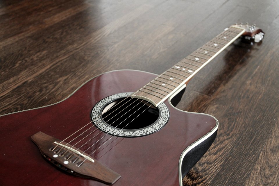 Red Acoustic Guitar Angled on Wood Floor