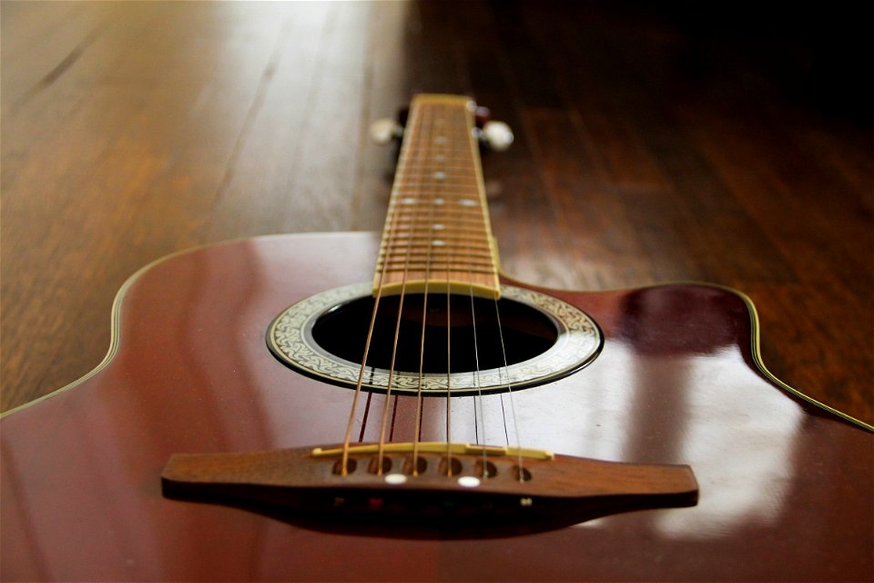 Red Acoustic Guitar on Wood Floor