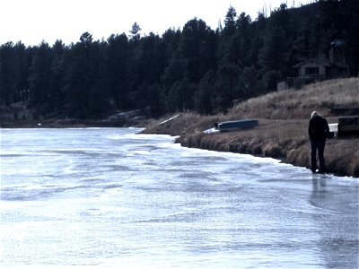 Woman Walking Along Edge of Frozen Lake photo