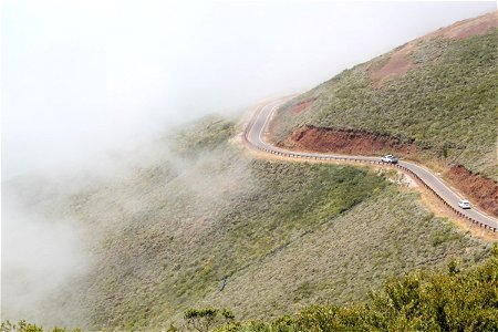 Cars Driving on Winding Mountain Road in Fog photo