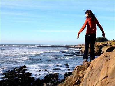 Girl Standing on Rocks on Ocean Coast photo