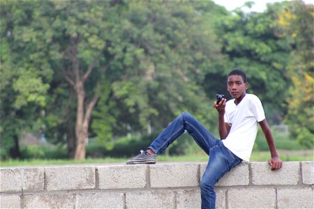 Teen Boy Sitting on Brick Wall with Camera photo