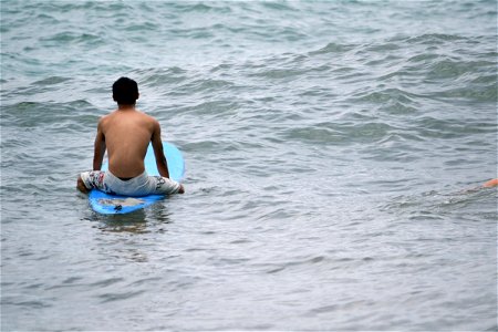 Man Sitting on Surfboard on Ocean photo