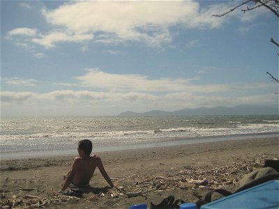 Guy Sitting on Beach Watching Ocean photo