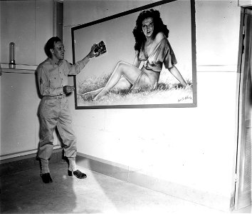 SC 374642 - Comparing his pin-up with the photo he used as a model, Sgt. Ervin Schweig, Hq. Co., TDRTC, wonders what the boys who use the day room think.
