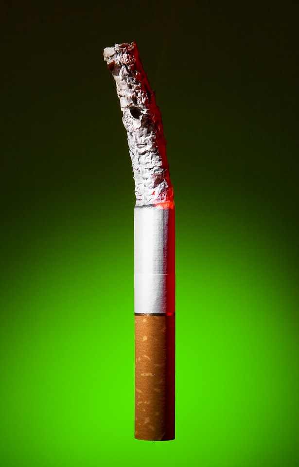 Burned cigarette on green background