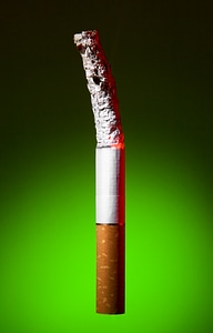 Burned cigarette on green background photo
