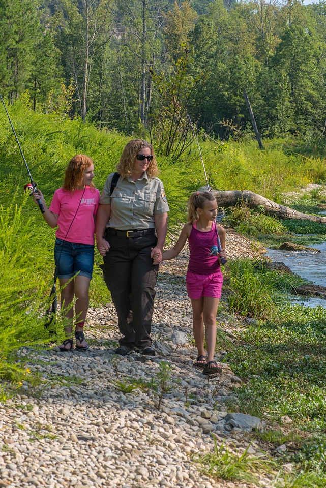 Uniformed FWS employee with two girls fishing