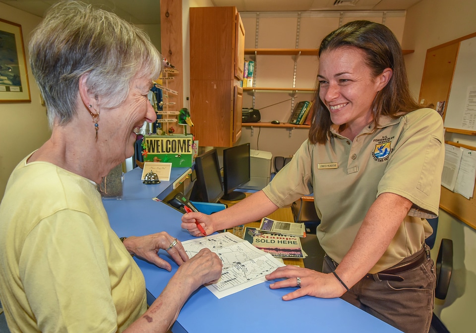 FWS Staffer greets visitor at visitor center desk