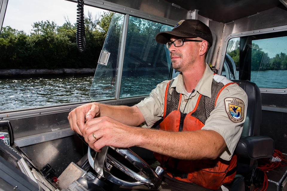 Fishery biologist pilots boat while collecting data on Asian carp