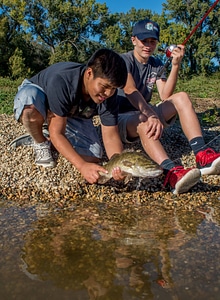 Two boys releasing small mouth bass