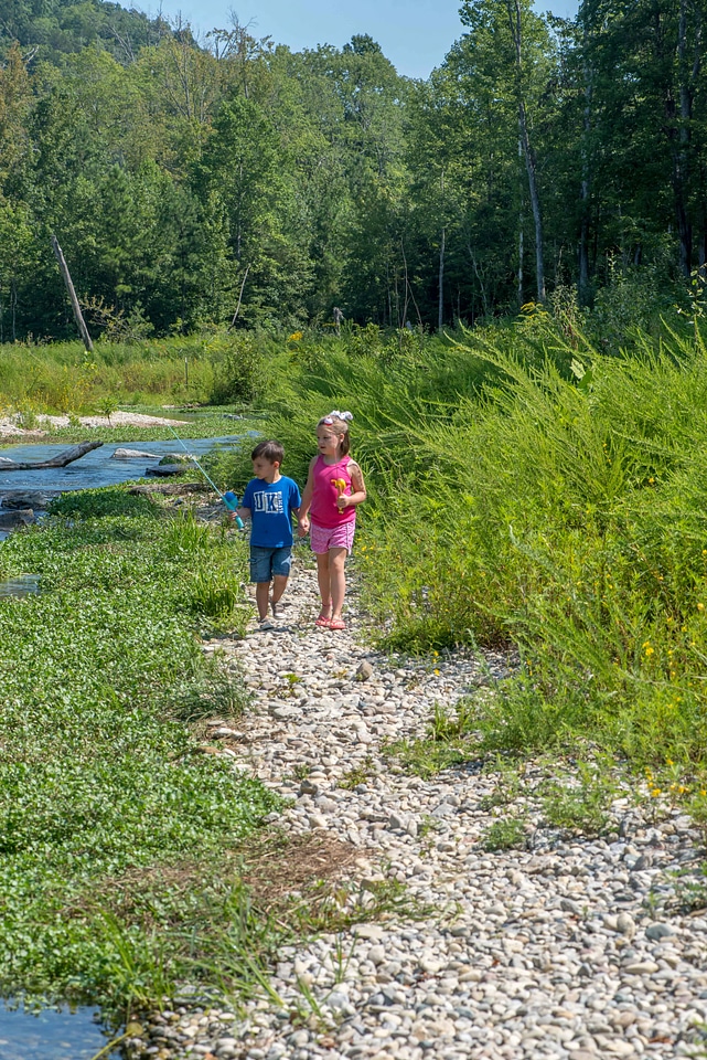 Little boy and girl going fishing, walking along creek-2