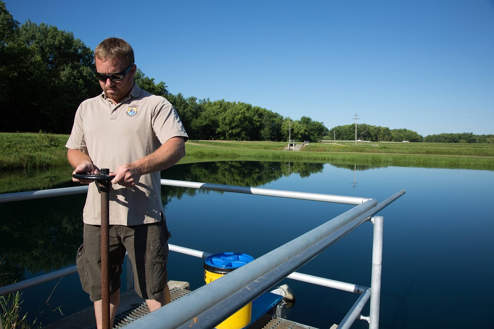 Fishery Biologist adjusts water flow to fish pond