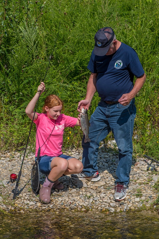 Older man with young redheaded girl and rainbow trout