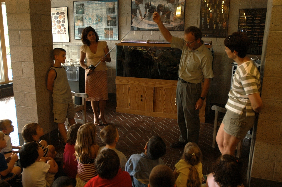 Service employee discusses the fishing pole to children