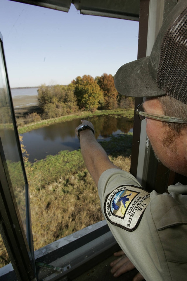 Service personnel point outside in the viewing area of the observation tower