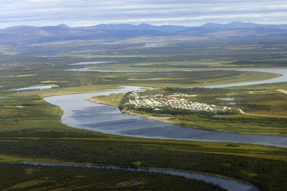 Aerial photo of a village, a waterway, and mountains in a remote area of Alaska