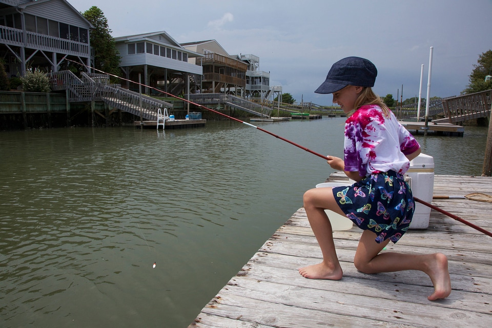 Girl lowering her fishing pole into the water