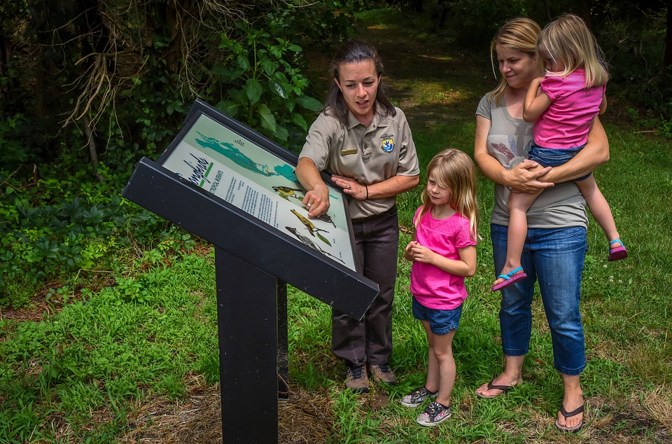FWS Visitor services staffer shows interpretive panel to family
