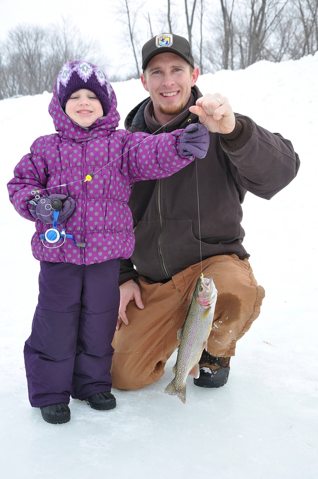 Fish & Wildlife Service employee assists young girl with her catch.