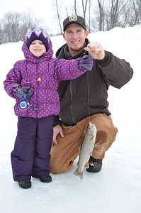 Fish & Wildlife Service employee assists young girl with her catch.