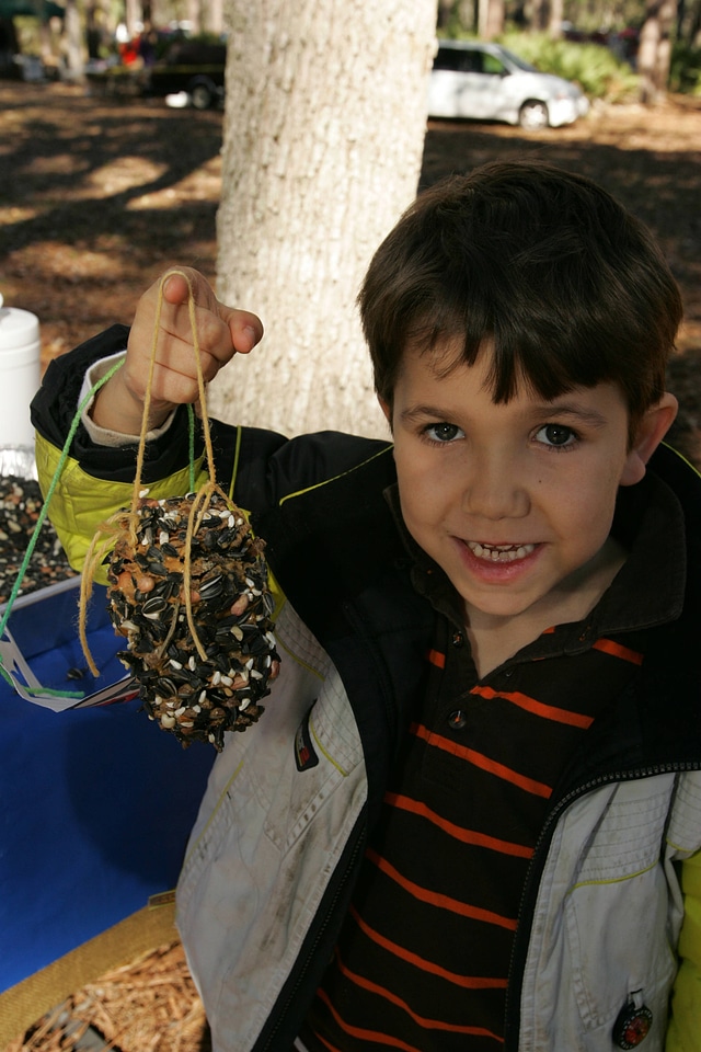 Child displays pinecone bird feeder