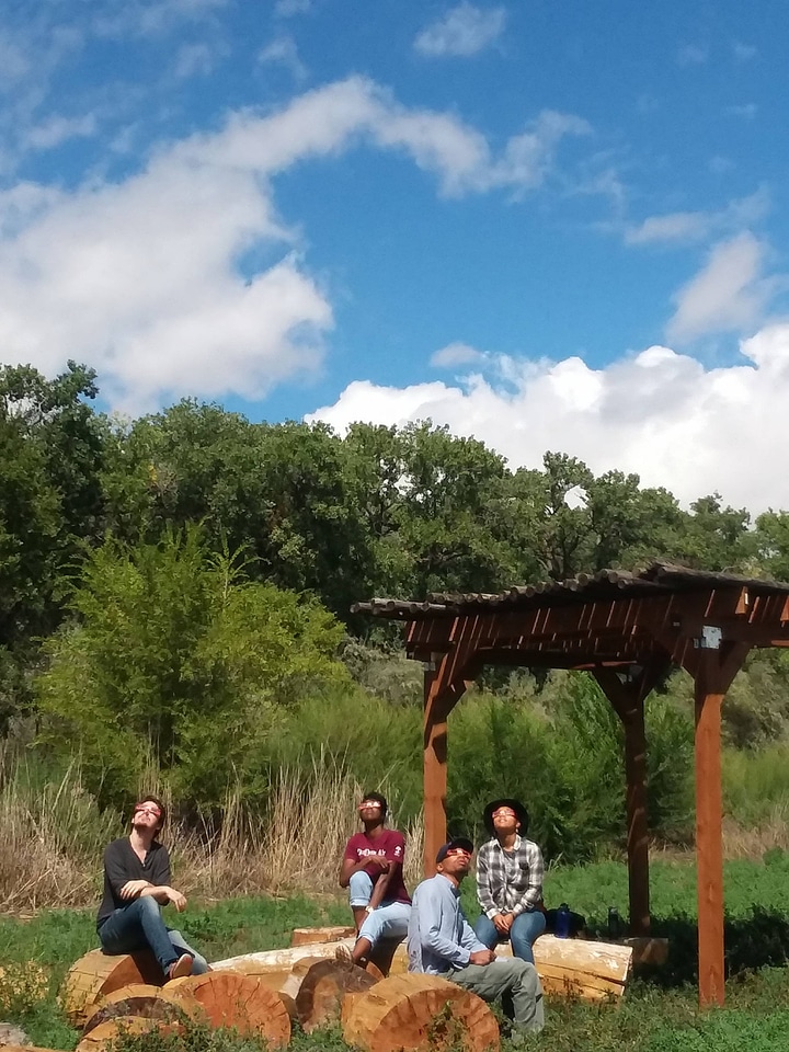 Group sits at Valle de Oro's outdoor classroom to watch the solar eclipse