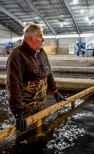 FWS employee prepares fish pump to load fish onto hatchery