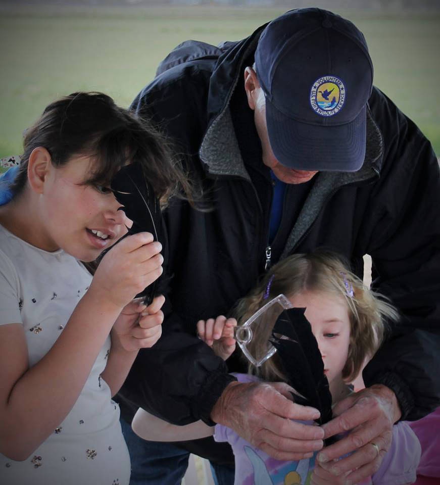 Refuge volunteer assisting young visitors with feather
