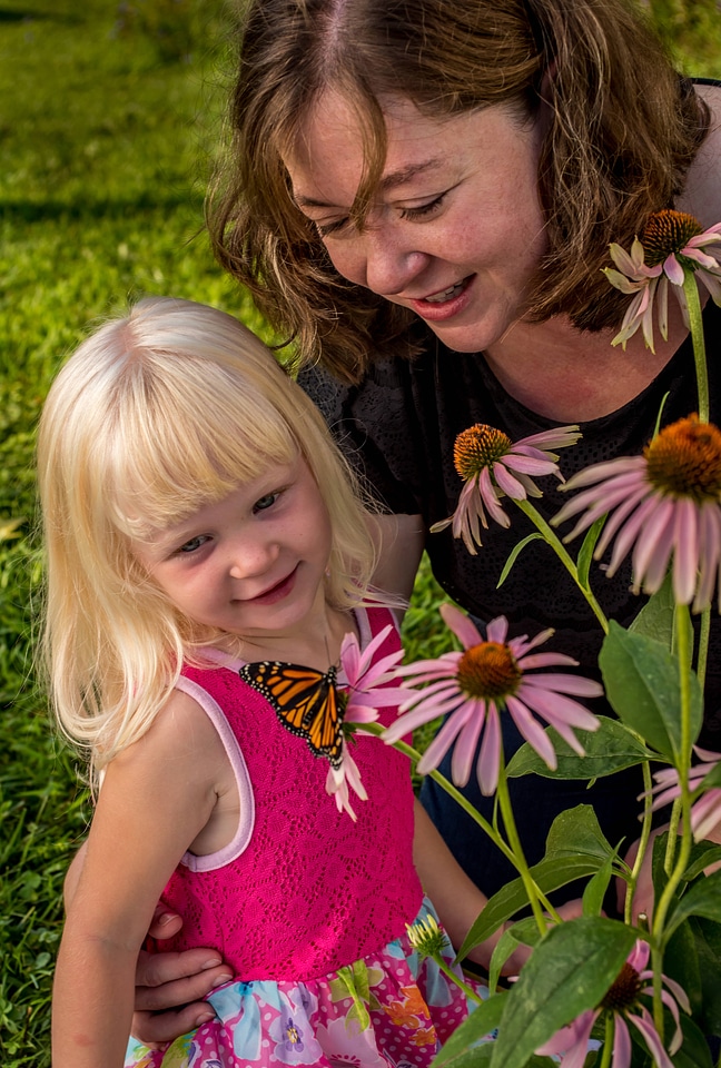 Mother and daughter look at monarch on flower-1
