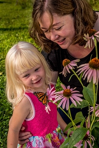 Mother and daughter look at monarch on flower-1