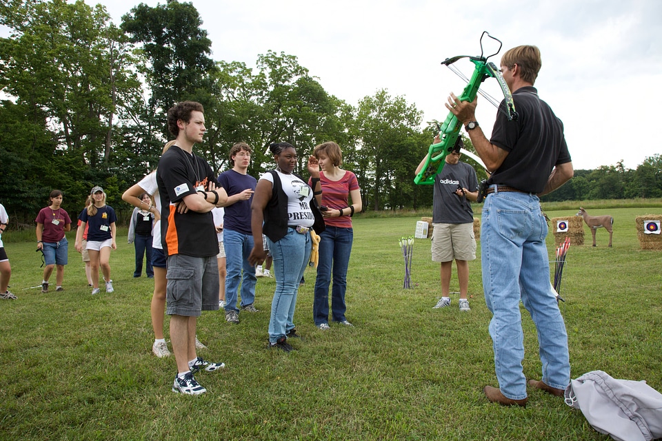 Service employee gives an archery demonstration to students