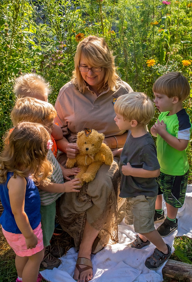 Children with fws employee look at monarch on stuffed bear